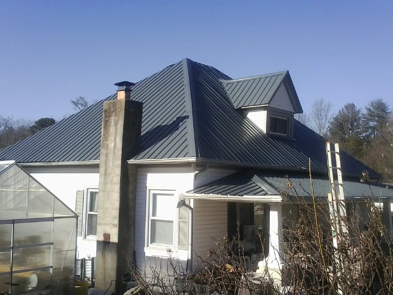 Dark blue standing seam metal roof on a white farmhouse with dormer — Slate & Tile Roof Repair by Roofing Brothers in Nome