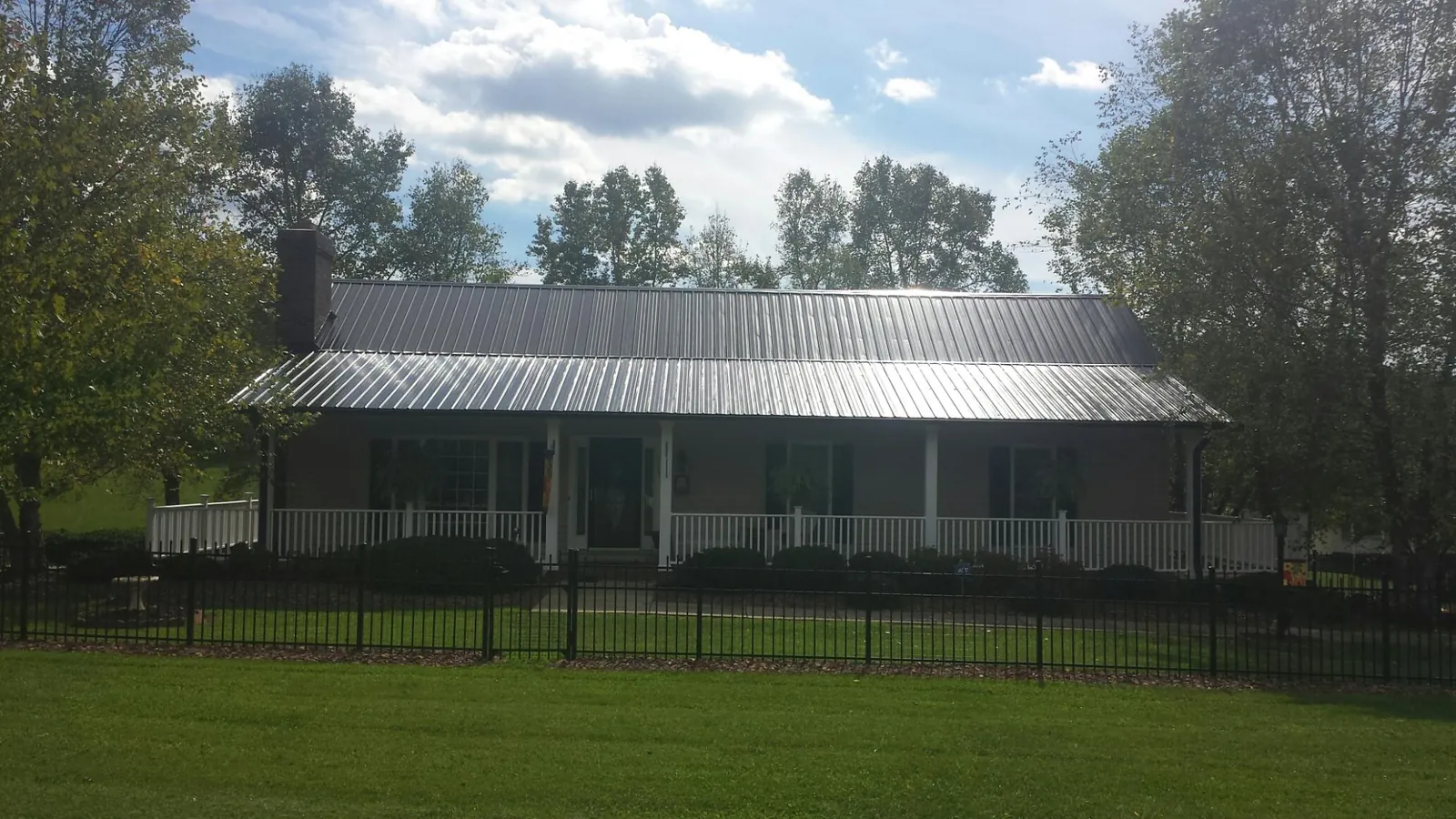 Gray metal roof on a brick ranch with a full width front porch — Gutter Guard Installation work by our crew in Nome