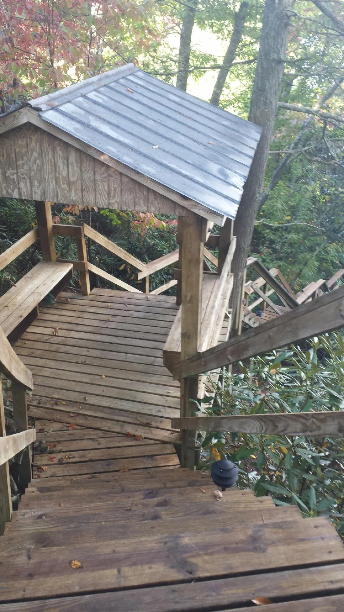 Metal roofed shelter over wooden steps on a wooded walkway — Skylight Repair & Installation work by our crew in Nome