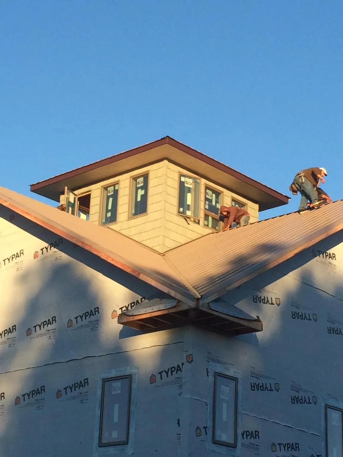 Roofers working around a rooftop cupola on a new metal roof at sunset — Roof Waterproofing in Nome by Roofing Brothers
